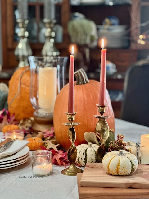 A Thanksgiving table with romantic inspiration and simplicity with pumpkins, leaves, brass candle sticks, & stacked. 3