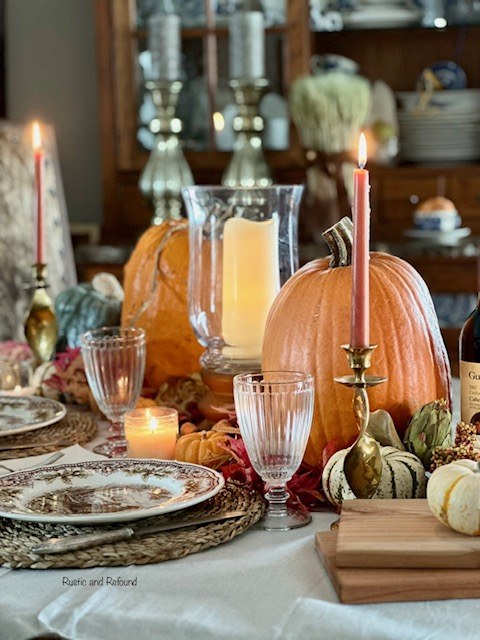 A Thanksgiving table with bold pumpkins, fall foliage, and candles. 6