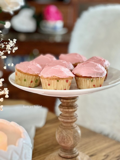 Seven pink cupcakes on a cake stand.