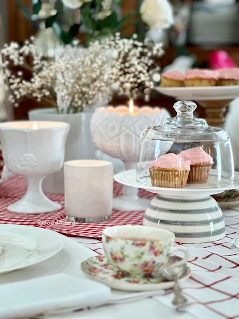 A Valentines table decorated flowers, candles and pink cupcakes.