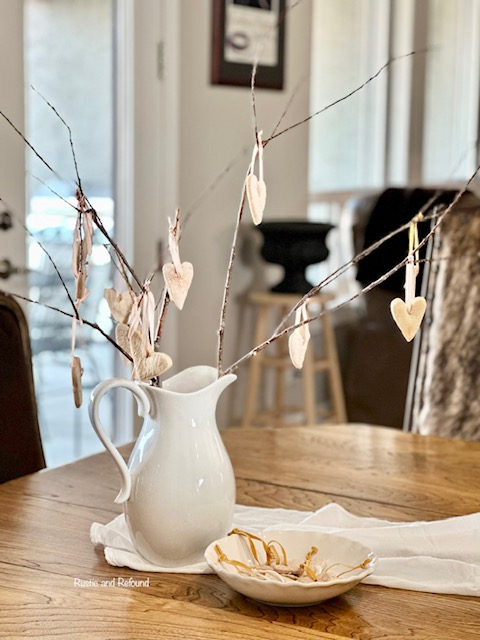 A salt dough ornaments hanging from a branch with pink ribbon.