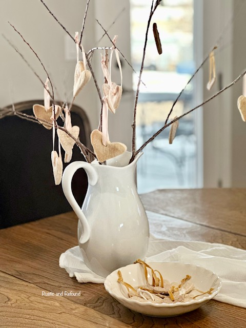 Valentine's Day DIY salt dough ornaments hanging from branches in a white pitcher.